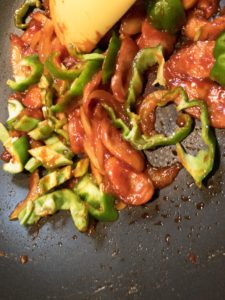 炒め詰めたナポリタンソースへピーマン投入